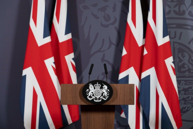 A government press conference lectern flanked by Union flags