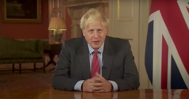Prime Minister Boris Johnson delivering a televised national address from a desk beside a Union flag