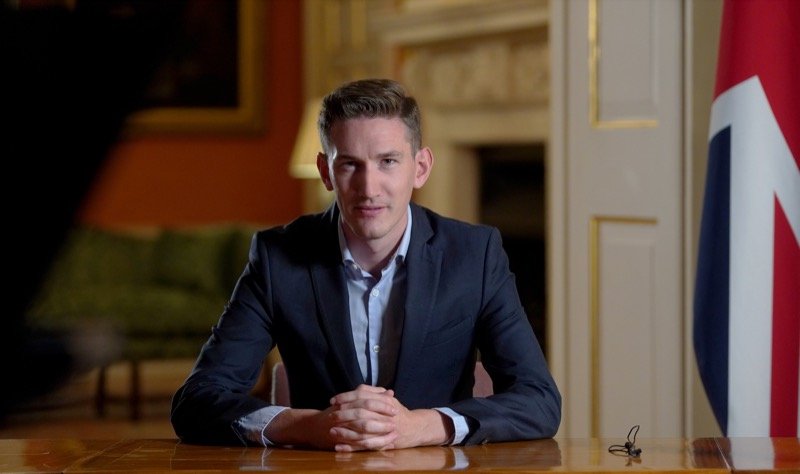 Robert Midgley seated at the same desk beside a Union flag