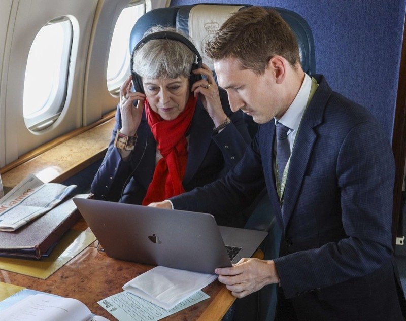 Robert Midgley showing footage on a laptop to Prime Minister Theresa May aboard a flight